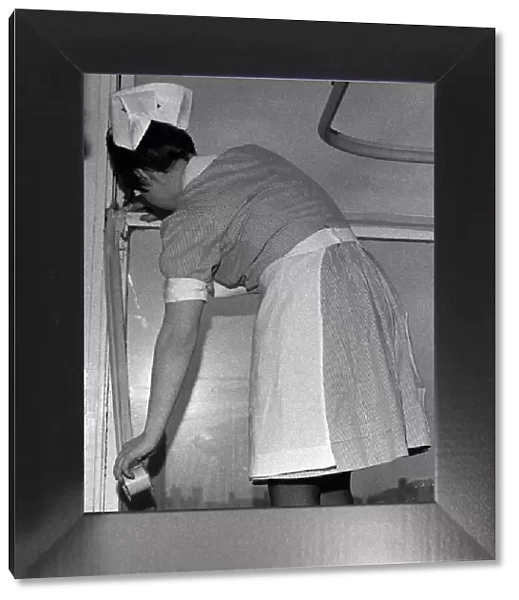 A nurse tapes up a draughty window in an Infirmary ward. 10th April 1970