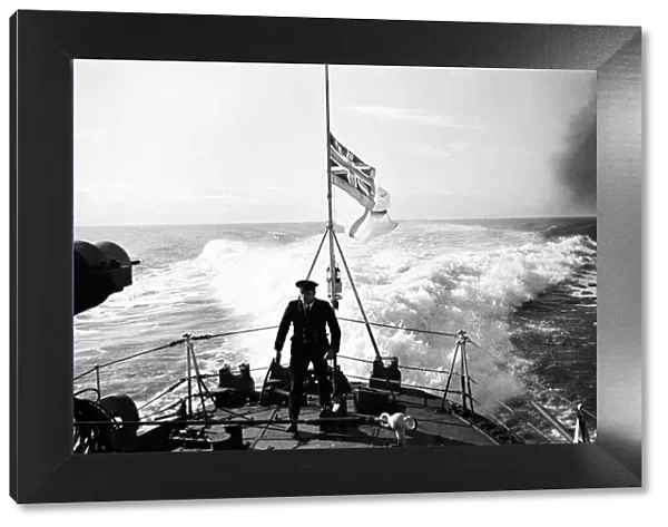 Petty Officer on the quarter deck of a Royal Naval destroyer, White Ensign at half mast