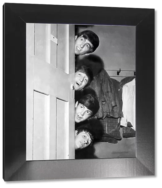 The Beatles peering out from behind their dressing room door before their appearance at
