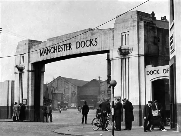 Only a few groups of men stand chatting at the gate of a deserted Manchester dock May