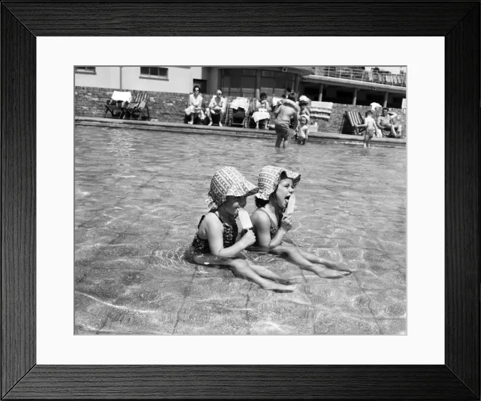 Framed Print : Hot weather scenes in Margate, Kent. Two young girls eating ice lollies while sitting in Framed Print : Hot weather scenes in Margate, Kent. Two young girls eating ice lollies while sitting in
