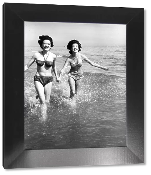 Hot weather scenes in Margate, Kent. Two young women running in the sea. 30th June 1961