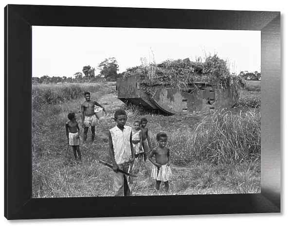 Children playing near a weed strewn Buffalo LVT American tank in a potato field