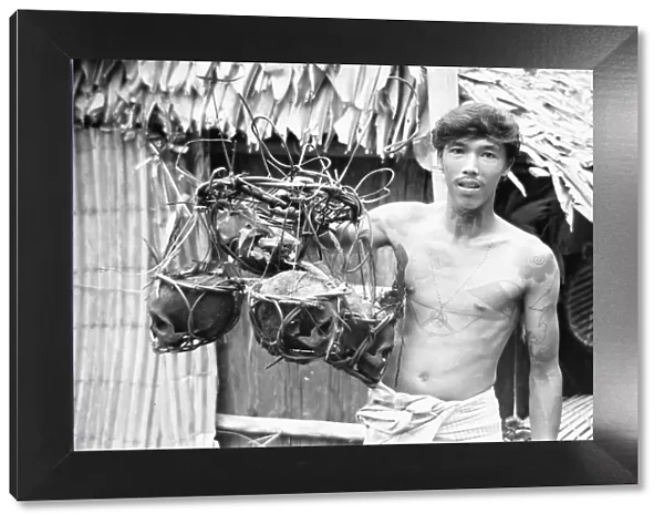 A Borneo headhunter tribesman seen here holding up a basket of human skulls