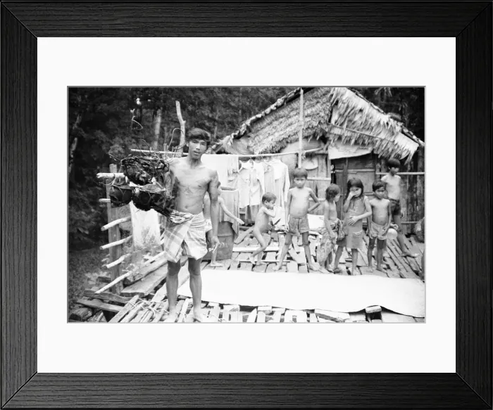 Framed Print : A Borneo headhunter tribesman seen here holding up a basket of human skulls Framed Print : A Borneo headhunter tribesman seen here holding up a basket of human skulls