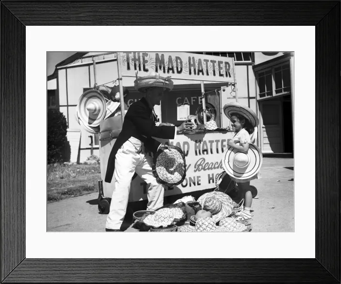 Framed Print : A young girl trying on a hat at The Mad Hatter stall, in Barry Island Framed Print : A young girl trying on a hat at The Mad Hatter stall, in Barry Island