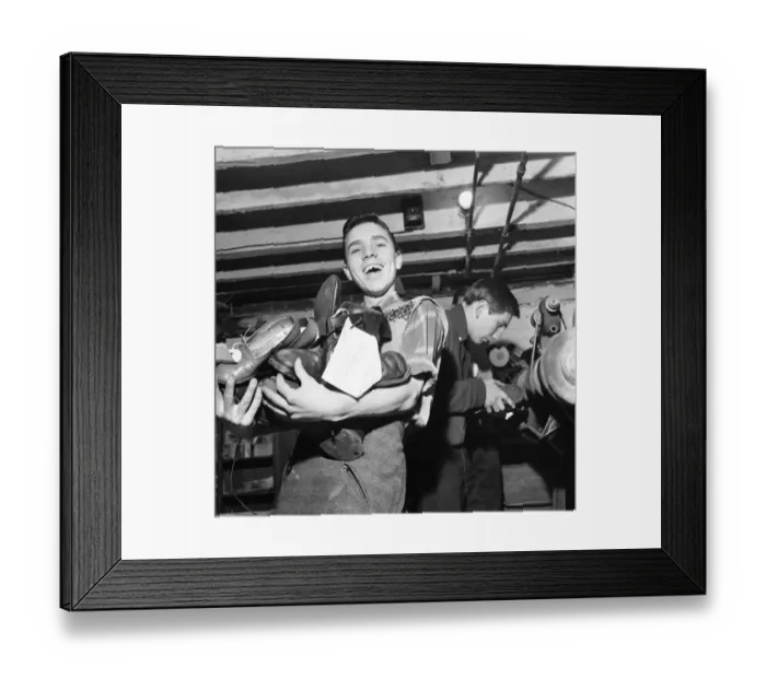 Framed Print : A boy carries a bundle of shoes. He is at work