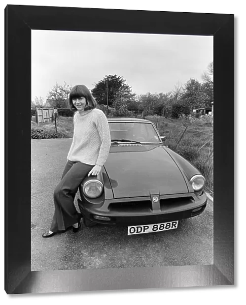 Pam Ayres poses beside her MGB sports car. 12th May 1977