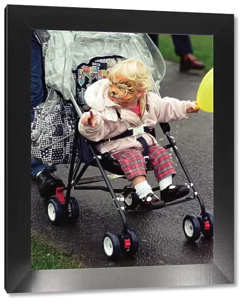 With her face painted this youngster toddled round in her pushchair during