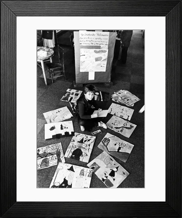 Framed Print : A young boy sitting on the floor among paintings and drawings which have been made by Framed Print : A young boy sitting on the floor among paintings and drawings which have been made by