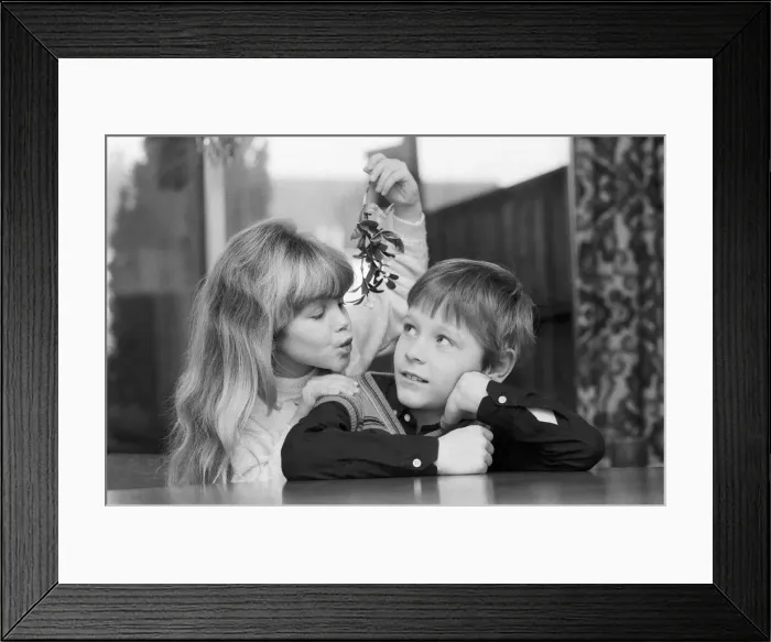 Framed Print : A young Girl with mistletoe attempts to kiss a young lad. 23rd December 1985 Framed Print : A young Girl with mistletoe attempts to kiss a young lad. 23rd December 1985