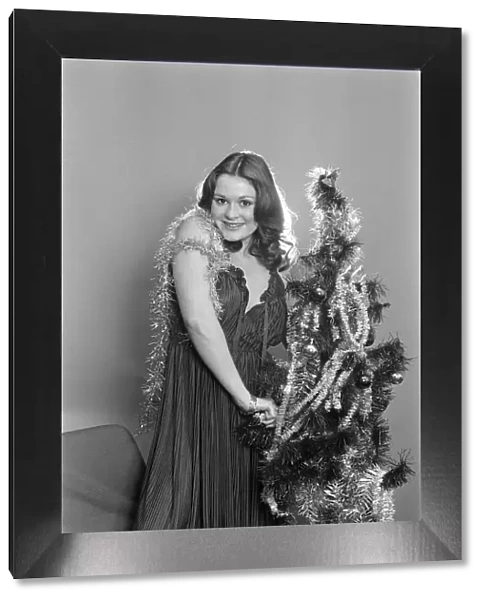 Model Leigh Lesley poses with a Christmas tree. 22nd December 1980