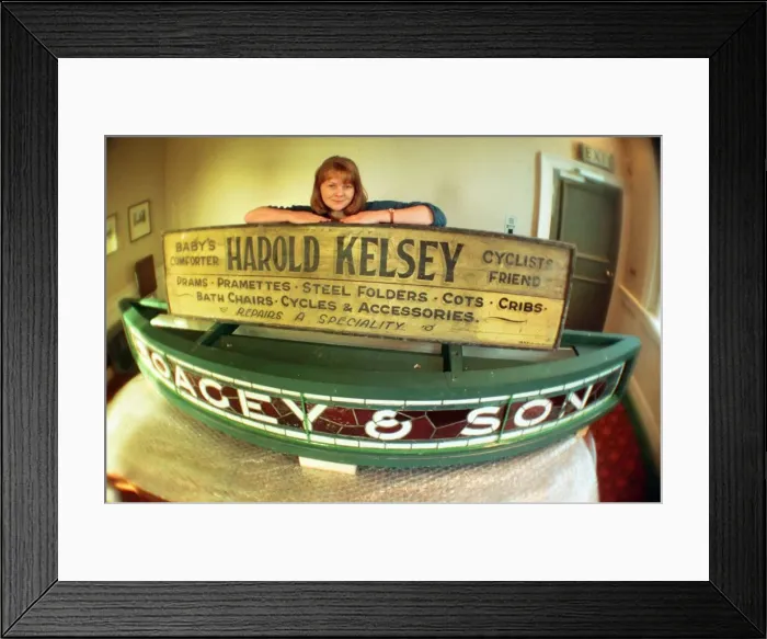 Framed Print : Kirkleatham Old Hall Museum curator Leigh Lampard with two of the old shop signs