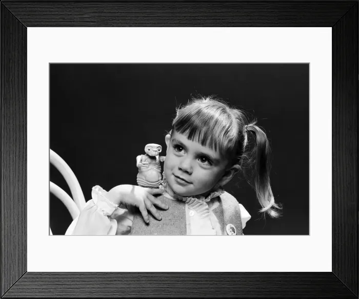 Framed Print : A young girl holding an E. T. from the film E. T. the Extra-Terrestrial. 5th December 1982