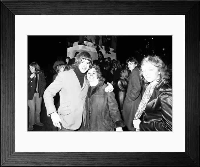 Framed Print : New Year revellers pose for the camera while in the background revellers climb the statue Framed Print : New Year revellers pose for the camera while in the background revellers climb the statue