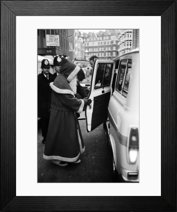 Framed Print : Santa is arrested by policeman for obstruction. He had been offering to pose with passers Framed Print : Santa is arrested by policeman for obstruction. He had been offering to pose with passers