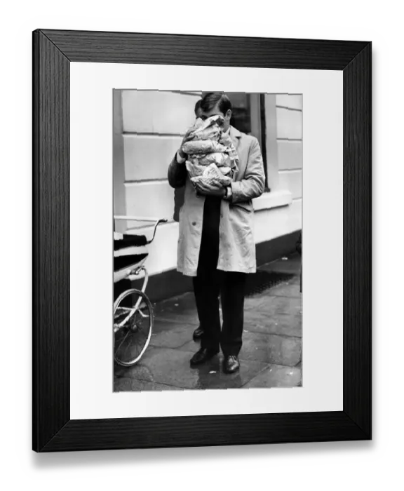 Framed Print : A man in the street holding Fish and Chips wrapped in newspaper