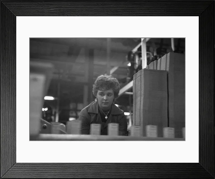 Framed Print : A young female employee checks that the machine has correctly filled Framed Print : A young female employee checks that the machine has correctly filled
