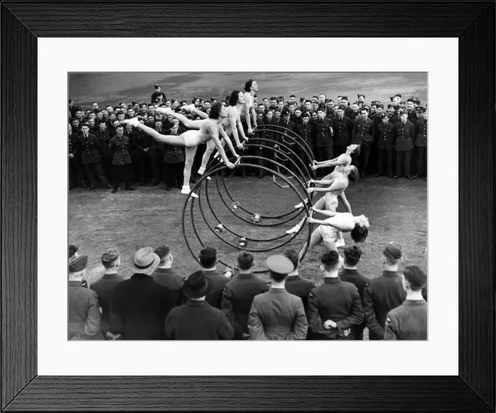 Framed Print : Women performing a gymnastic routine with large metal hoops, watched by military men Framed Print : Women performing a gymnastic routine with large metal hoops, watched by military men