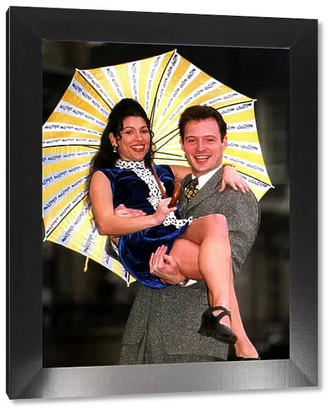 Kathryn Dixon being lifted by John Leslie holding yellow and white striped umbrella