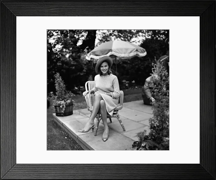 Framed Print : Actress Honor Blackman relaxes in her garden party outfit during the filming of