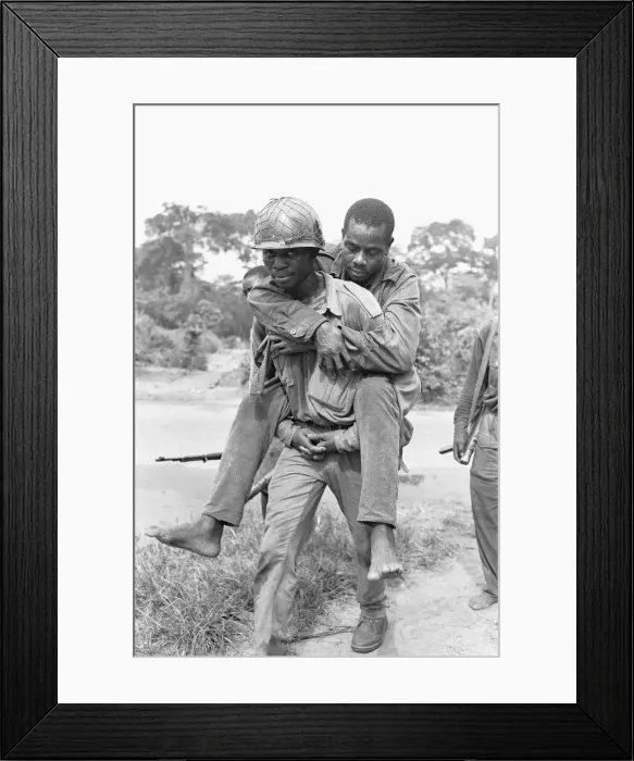 Framed Print : A wounded Biafran soldier is given a piggy-back to a field dressing station following an Framed Print : A wounded Biafran soldier is given a piggy-back to a field dressing station following an