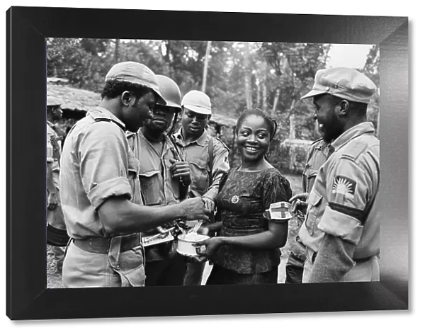 Biafran soldiers seen here enjoying some food held by an aid worker during the Biafran