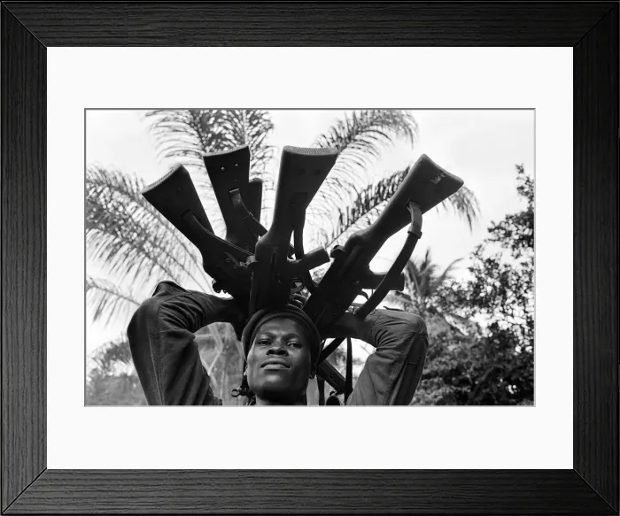 Framed Print : A Biafran soldier seen here holding a selection of guns during the Biafran conflict Framed Print : A Biafran soldier seen here holding a selection of guns during the Biafran conflict