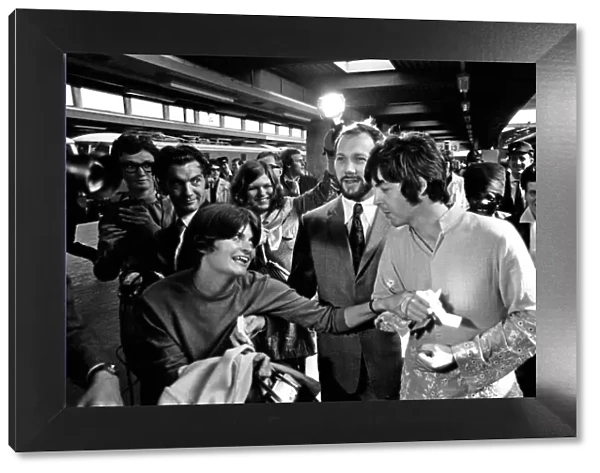 Paul McCartney has his hand held by a fan as The Beatles leave London Euston Station for