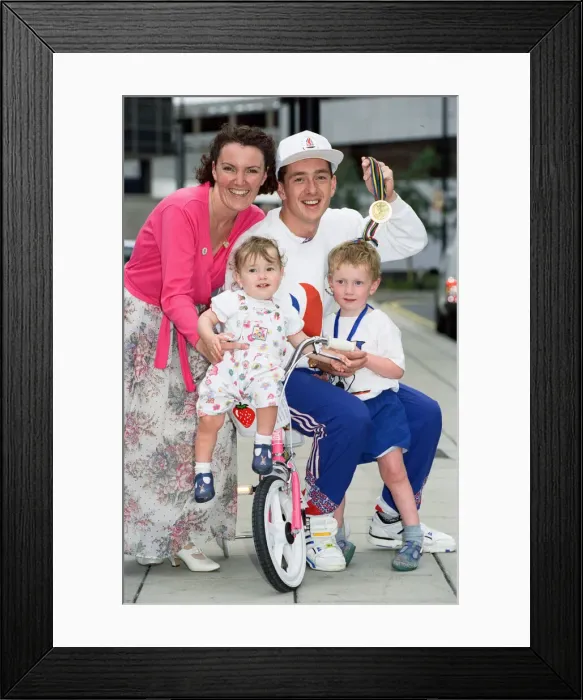 Framed Print : British cyclist Chris Boardman poses with his family on arrival at Manchester airport as Framed Print : British cyclist Chris Boardman poses with his family on arrival at Manchester airport as