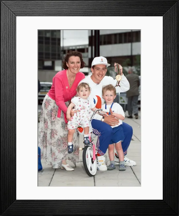 Framed Print : British cyclist Chris Boardman poses with his family on arrival at Manchester airport as Framed Print : British cyclist Chris Boardman poses with his family on arrival at Manchester airport as