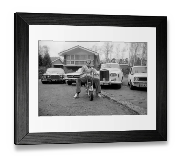 Framed Print : Elton John pictured at his home, sitting on a small motorbike in front of four of his Framed Print : Elton John pictured at his home, sitting on a small motorbike in front of four of his