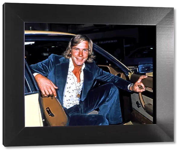 James Hunt, smiles to camera, whilst sitting in the front seat of his car