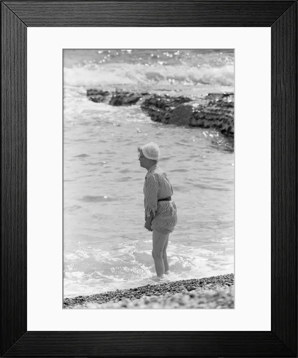 Framed Print : Holiday scenes at Brighton Elderly women paddling on the beach holding her skirt