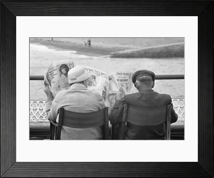 Framed Print : Holiday scenes at Brighton. Elderly couple reading the Daily Herald on Brighton