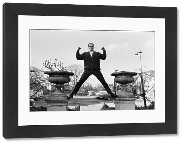 Henry Cooper, pictured standing astride two ornamental flower pots in the garden of The