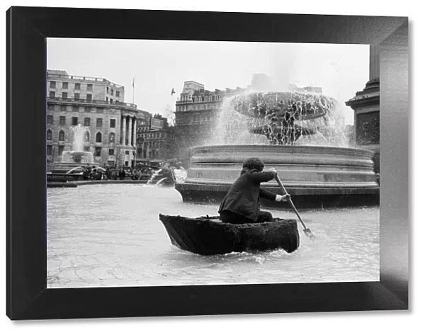 Coracle fishermen in London. One of the fishermen paddles his coracle round Trafalgar
