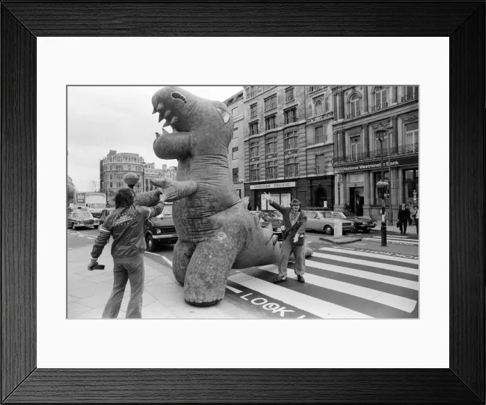 Framed Print : Two dinosaurs as high as a double decker bus fight each other in London Framed Print : Two dinosaurs as high as a double decker bus fight each other in London