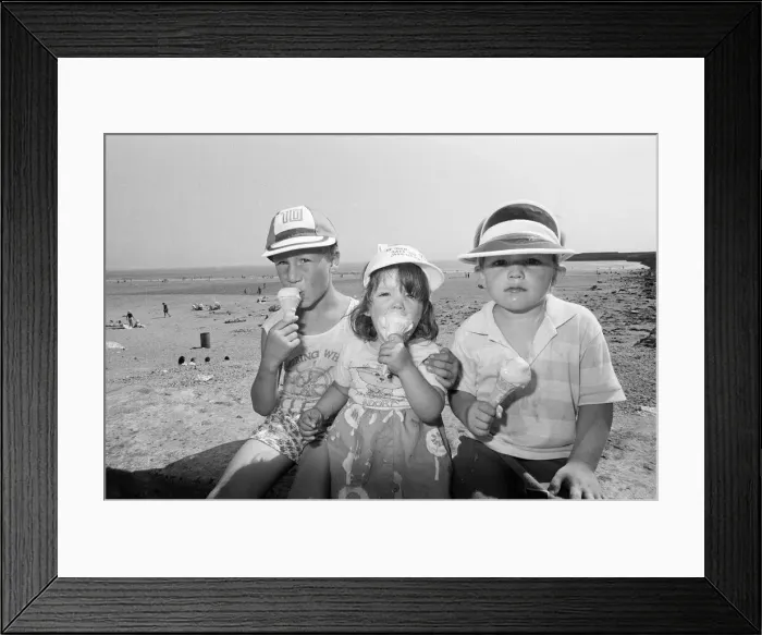 Framed Print : Children enjoy an ice cream as they try to keep cool on Coney Beach in Porthcawl