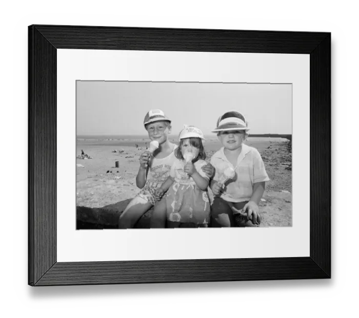 Framed Print : Children enjoy an ice cream as they try to keep cool on Coney Beach in Porthcawl