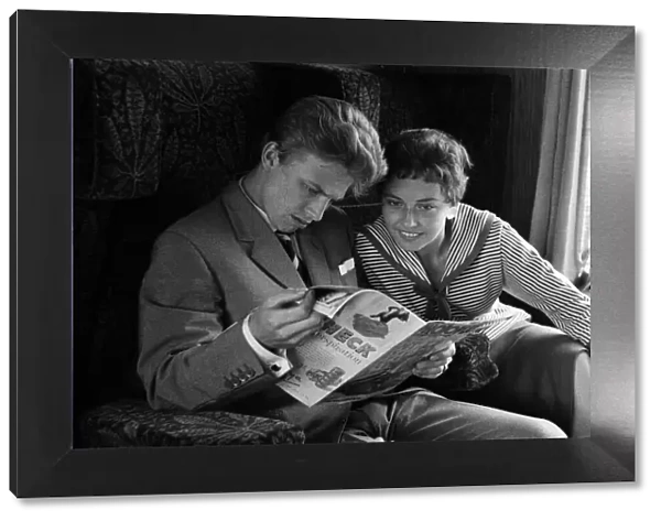 A young couple on a train, reading a copy of Photoplay magazine
