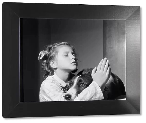 A girl and dog praying. 21st December 1954