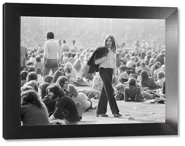 A long haired music fan, jack over his shoulder, wanders through the huge crowd
