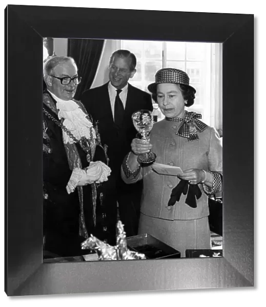 The Queen examines a Royal Doulton crystal goblet presented to her by the Lord Mayor