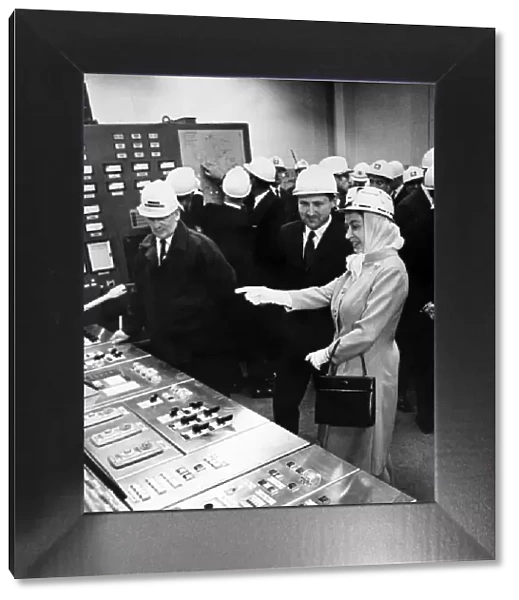 Queen Elizabeth II wearing protective clothing, watches the control panel of the new