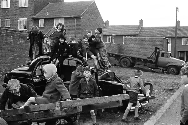Children play on the wreck of a dumped car at Kirkby, Liverpool. 18th March 1965