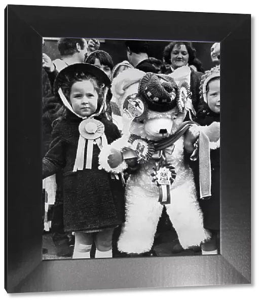 Young female fans of Skelmersdale Football club holding a giant mascot teddy bear as they