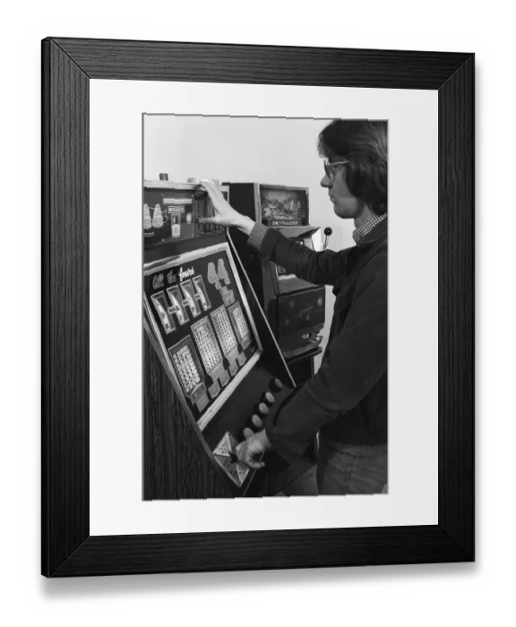 Framed Print : Man playing a one arm bandit slot machine in a London amusement arcade. 8th January 1975 Framed Print : Man playing a one arm bandit slot machine in a London amusement arcade. 8th January 1975