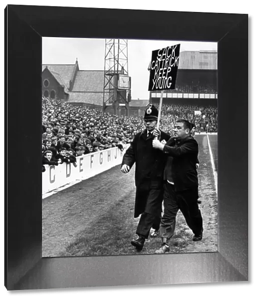 A fan being escorted off the football pitch by a policeman
