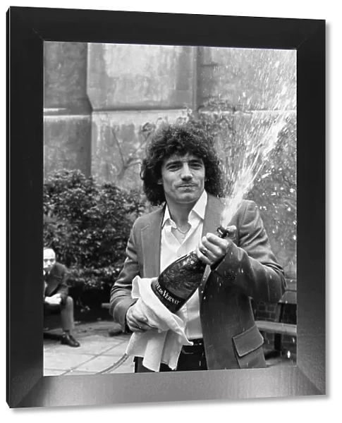 England footballer Kevin Keegan poses for photographers holding a large champagne bottle